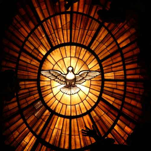 Eine erleuchtete Taube auf einem Kirchenfenster im Flug